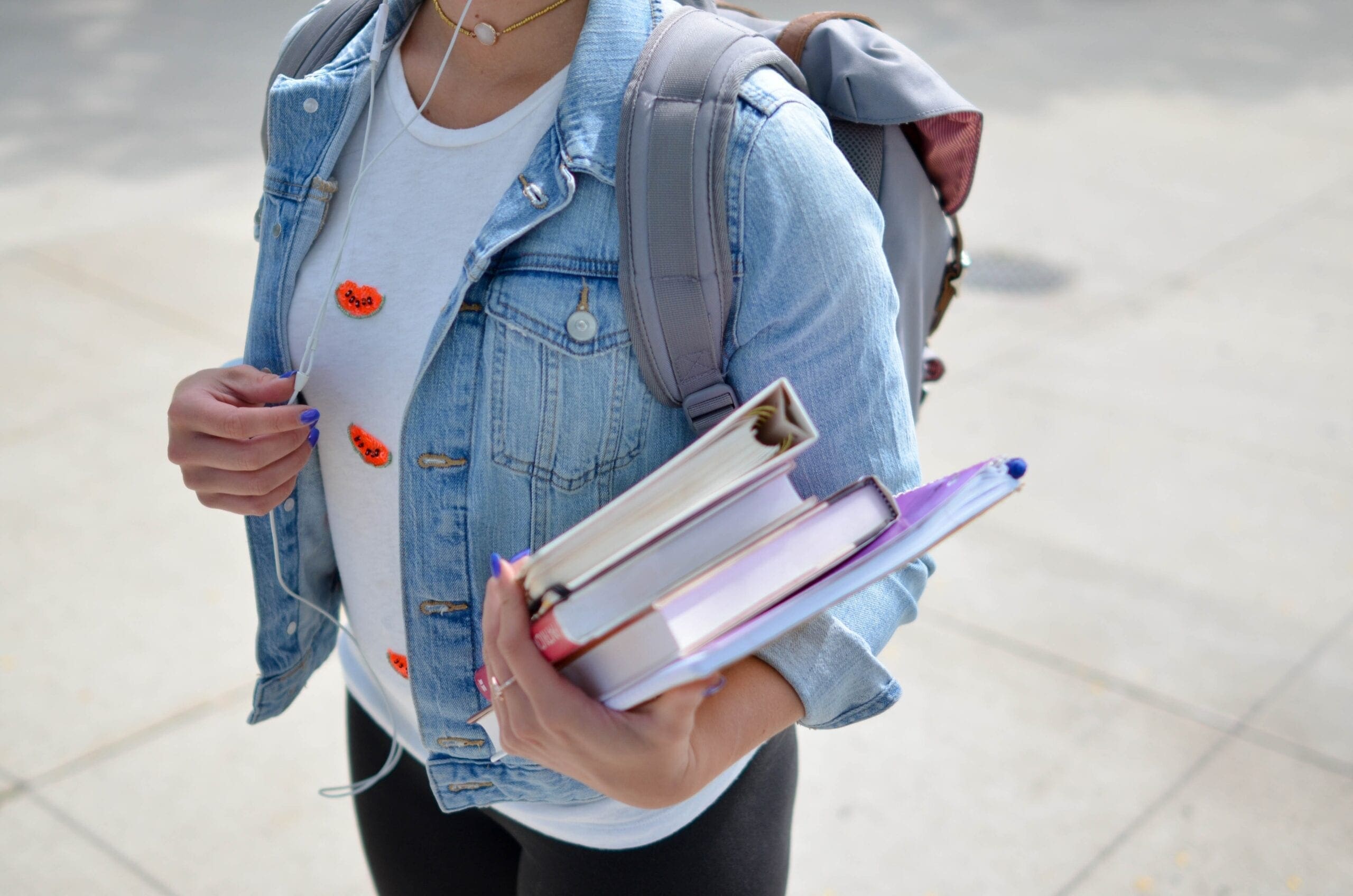 girl carrying school backpack and books